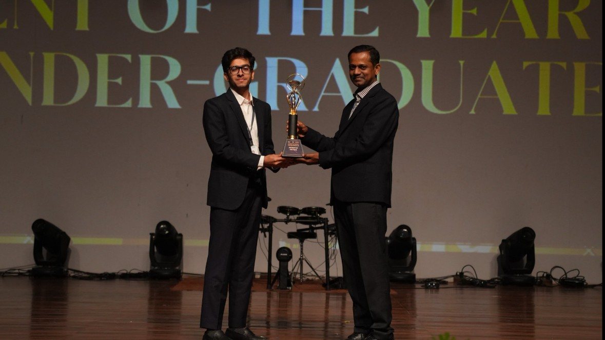Samkit receiving the Student of the Year trophy on stage